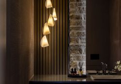 Luxury powder room with layeres of organic finishes, ranging from grass cloth, custom hand formed porcelain bocci pendants, vertical oak batten and fond du lac natural stone